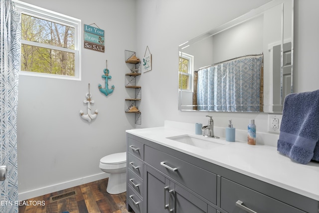 full bathroom with wood finished floors, vanity, baseboards, toilet, and visible vents