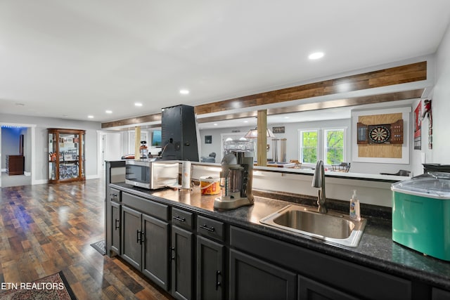 kitchen with dark wood finished floors, dark countertops, recessed lighting, and a sink