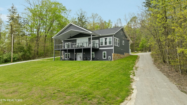 view of front of home with dirt driveway, a front yard, and a deck