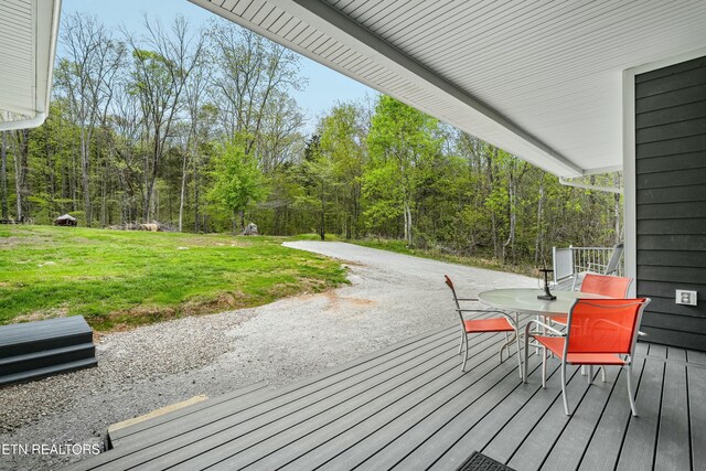 wooden deck with a lawn and a wooded view
