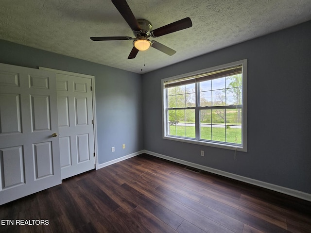 unfurnished bedroom with baseboards, dark wood-type flooring, visible vents, and a textured ceiling