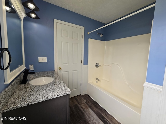 full bath featuring washtub / shower combination, wood finished floors, a textured ceiling, and vanity