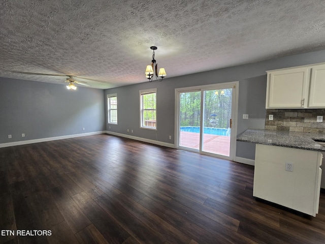 interior space featuring baseboards, a textured ceiling, and dark wood finished floors