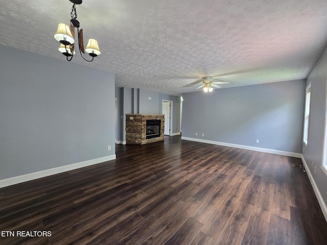 unfurnished living room with a textured ceiling, dark wood-style flooring, baseboards, ceiling fan with notable chandelier, and a fireplace