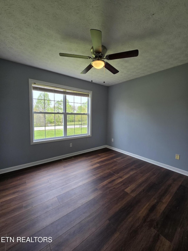 unfurnished room featuring a textured ceiling, ceiling fan, dark wood finished floors, baseboards, and visible vents