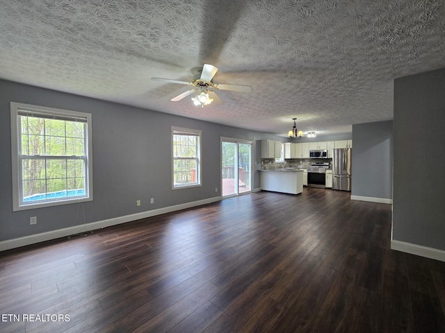 unfurnished living room featuring a textured ceiling, baseboards, dark wood-style flooring, and ceiling fan with notable chandelier