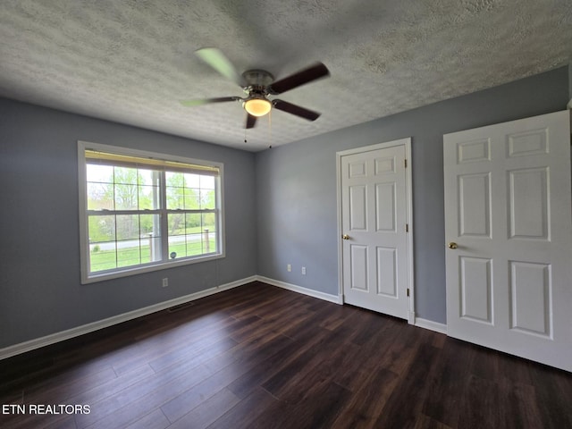unfurnished bedroom with a ceiling fan, baseboards, a textured ceiling, and dark wood finished floors