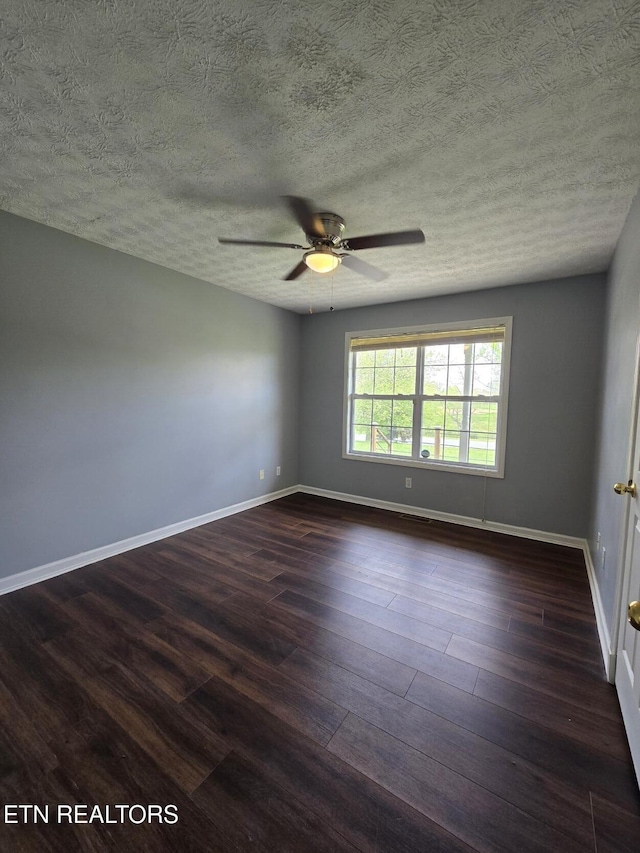 spare room featuring baseboards, a textured ceiling, dark wood-style floors, and ceiling fan