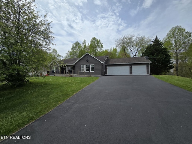 ranch-style house featuring an attached garage, a front yard, and aphalt driveway