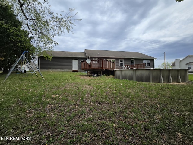 back of property featuring a lawn, an outdoor pool, and a deck