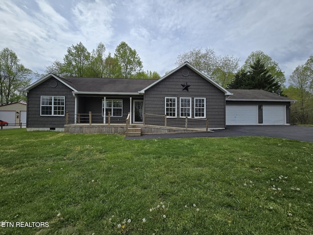ranch-style home with covered porch, a front yard, and a detached garage