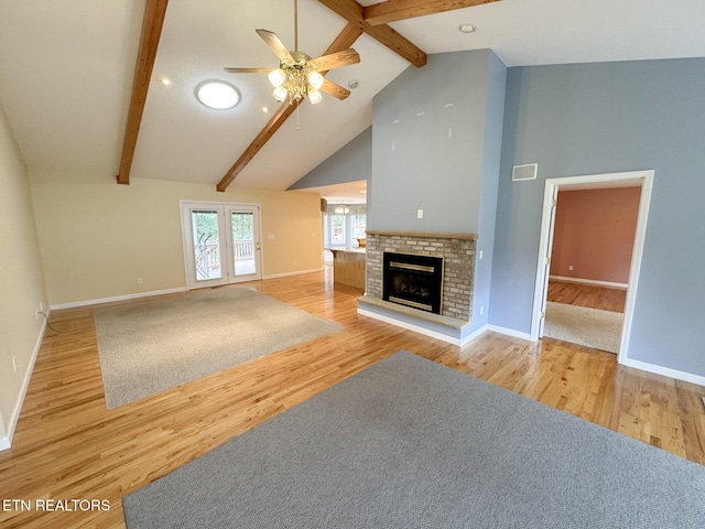 76 Sundrop Ln, Crossville, TN 38571 - unfurnished living room with ceiling fan, beamed ceiling, wood finished floors, a brick fireplace, and high vaulted ceiling