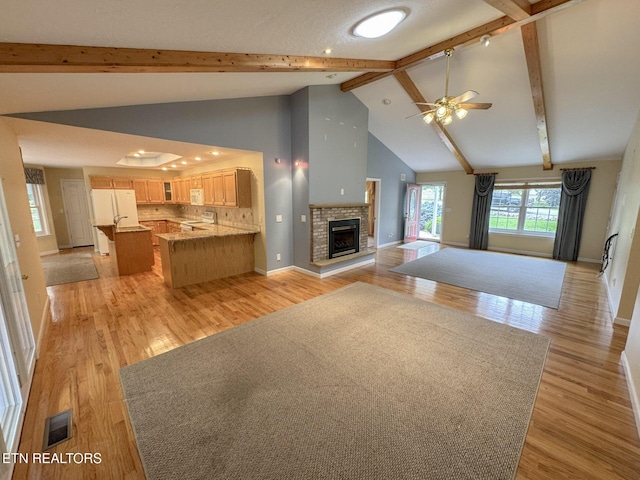 76 Sundrop Ln, Crossville, TN 38571 - unfurnished living room with a brick fireplace, ceiling fan, beamed ceiling, light wood-style flooring, and high vaulted ceiling