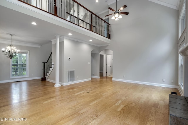 100 Coyatee Cir, Loudon, TN 37774 - unfurnished living room with stairs, ceiling fan with notable chandelier, a towering ceiling, visible vents, and arched walkways
