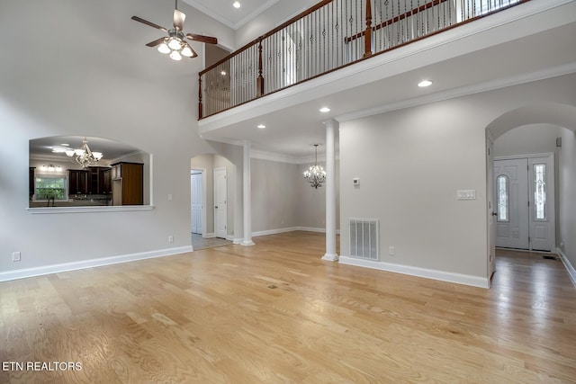 100 Coyatee Cir, Loudon, TN 37774 - unfurnished living room featuring light wood finished floors, ceiling fan with notable chandelier, visible vents, a towering ceiling, and arched walkways