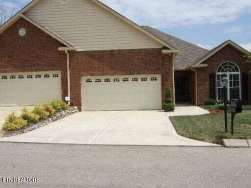view of front facade featuring concrete driveway, brick siding, and a garage
