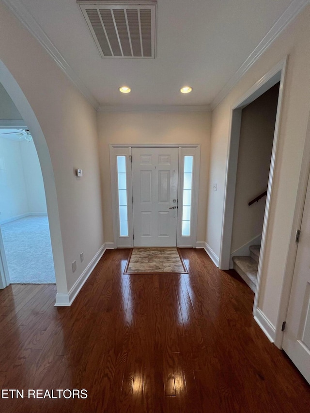 foyer featuring crown molding, dark wood-style flooring, arched walkways, stairs, and visible vents