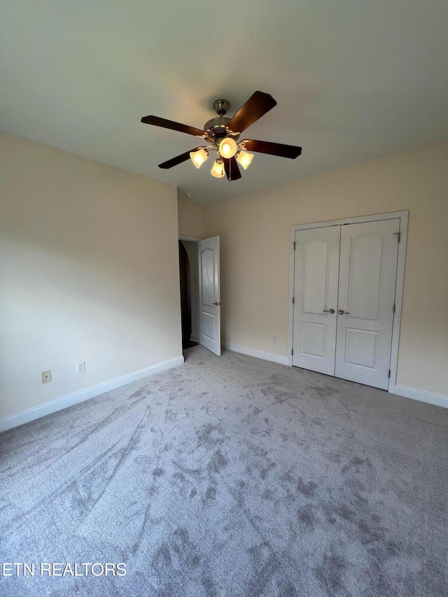 unfurnished bedroom with baseboards, ceiling fan, carpet, and a closet