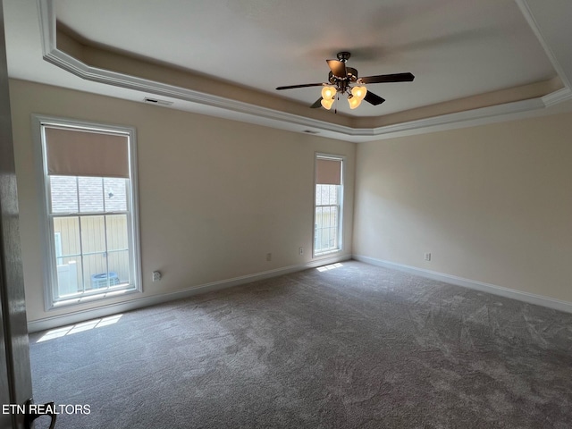 empty room featuring carpet floors, visible vents, baseboards, a tray ceiling, and a ceiling fan