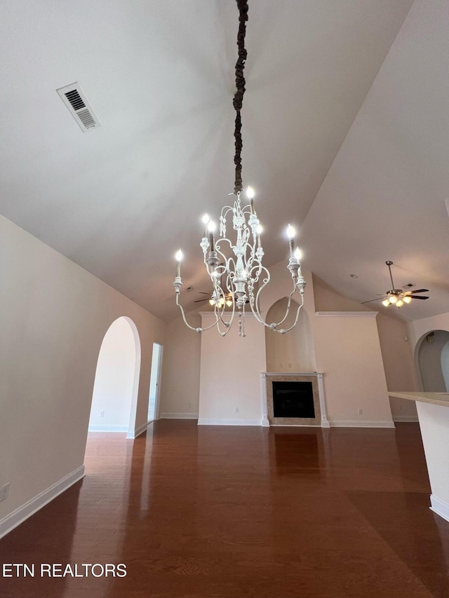 unfurnished living room featuring visible vents, a fireplace, arched walkways, ceiling fan with notable chandelier, and vaulted ceiling