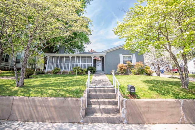 view of front of house featuring a chimney, a sunroom, and a front yard