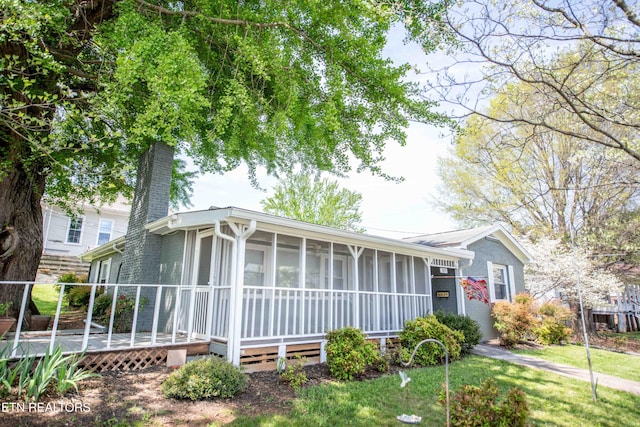 view of front of house featuring a chimney, a sunroom, and a deck