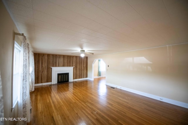 unfurnished living room featuring wood finished floors, visible vents, baseboards, a fireplace, and ceiling fan