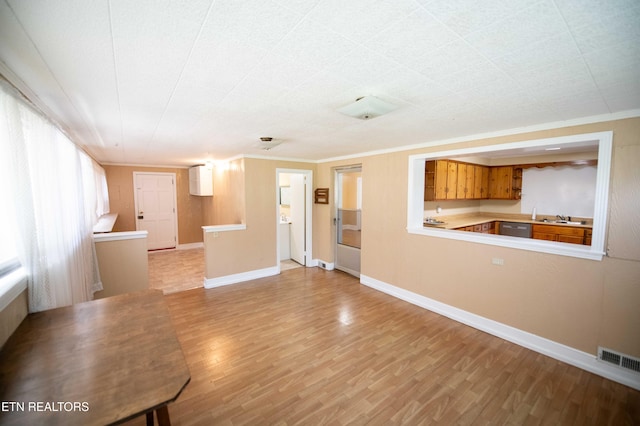unfurnished living room featuring light wood-type flooring, baseboards, visible vents, and a sink