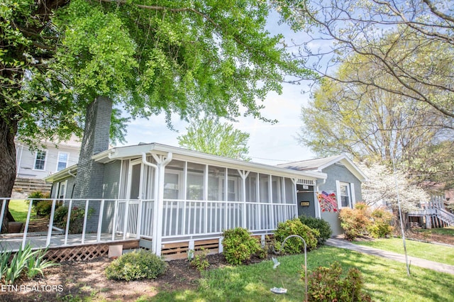 view of front of house featuring a chimney, a sunroom, and a deck