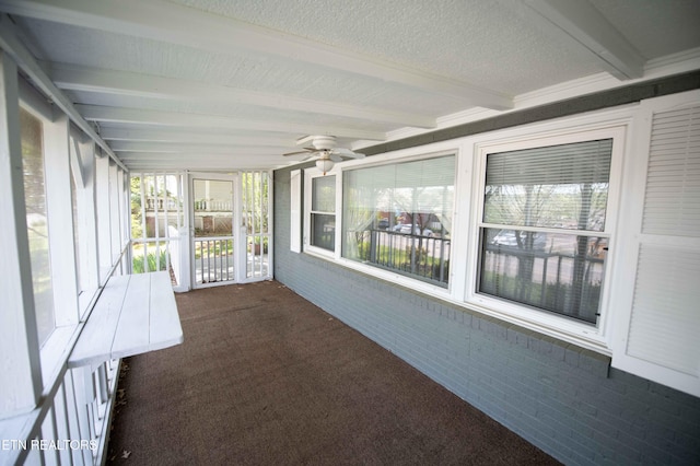 unfurnished sunroom featuring plenty of natural light, a ceiling fan, and beam ceiling