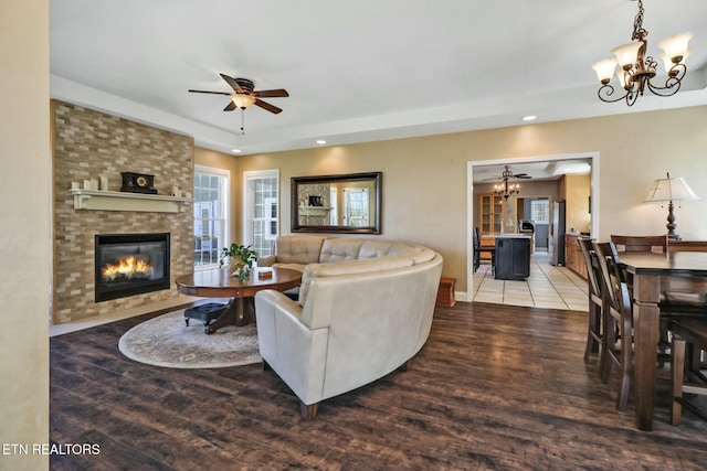 living room featuring a fireplace, wood finished floors, recessed lighting, and ceiling fan with notable chandelier