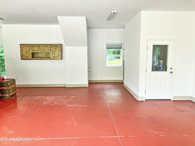 unfurnished living room featuring baseboards and finished concrete flooring