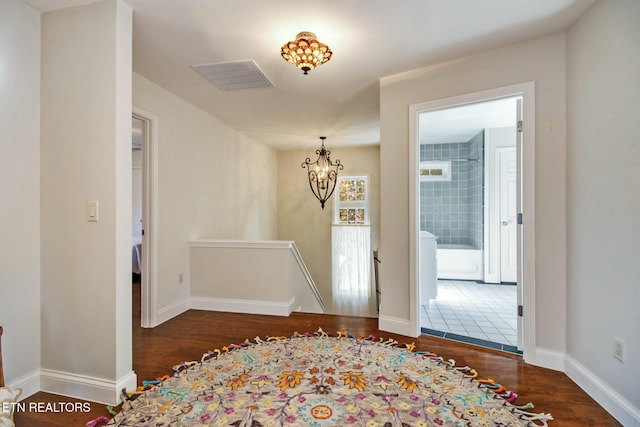 interior space with an inviting chandelier, wood finished floors, an upstairs landing, and visible vents