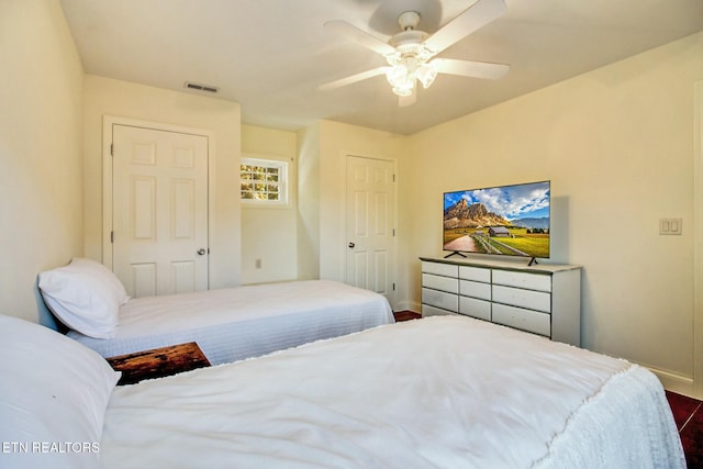 bedroom with baseboards, a ceiling fan, dark wood-type flooring, and visible vents