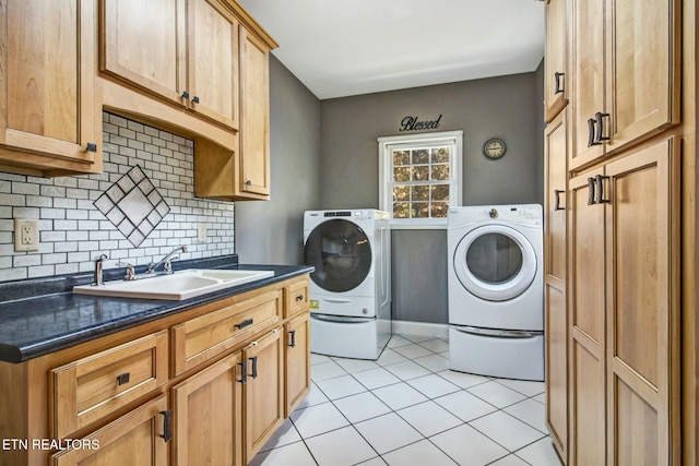 laundry area featuring washing machine and dryer, a sink, light tile patterned floors, and cabinet space