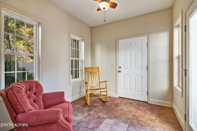 living area with a ceiling fan, baseboards, and tile patterned flooring