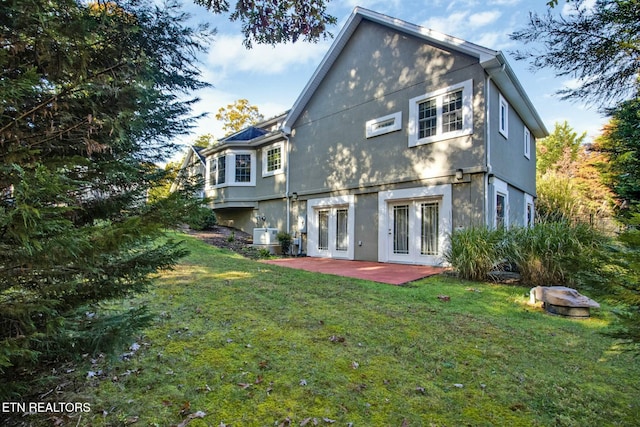 rear view of house featuring a patio area, a lawn, and stucco siding