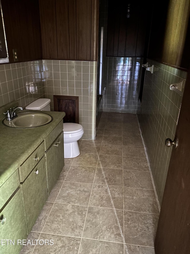 bathroom featuring toilet, vanity, and tile walls
