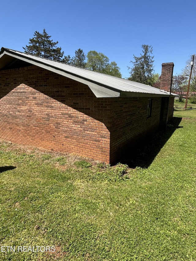 view of side of home with a lawn and a chimney