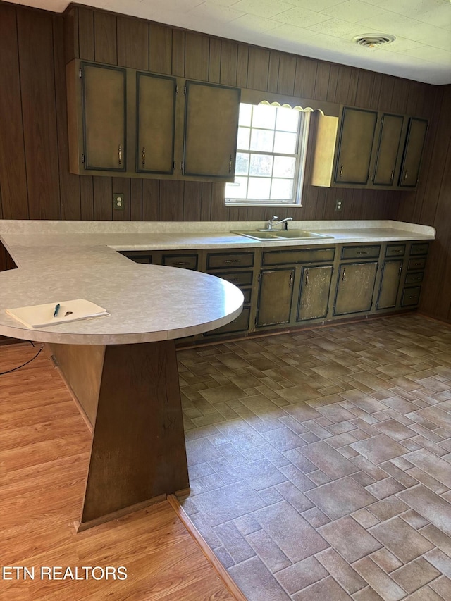 kitchen featuring a peninsula, a sink, visible vents, and light countertops