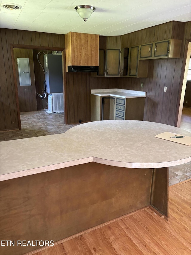 kitchen with light countertops, wooden walls, visible vents, and electric panel