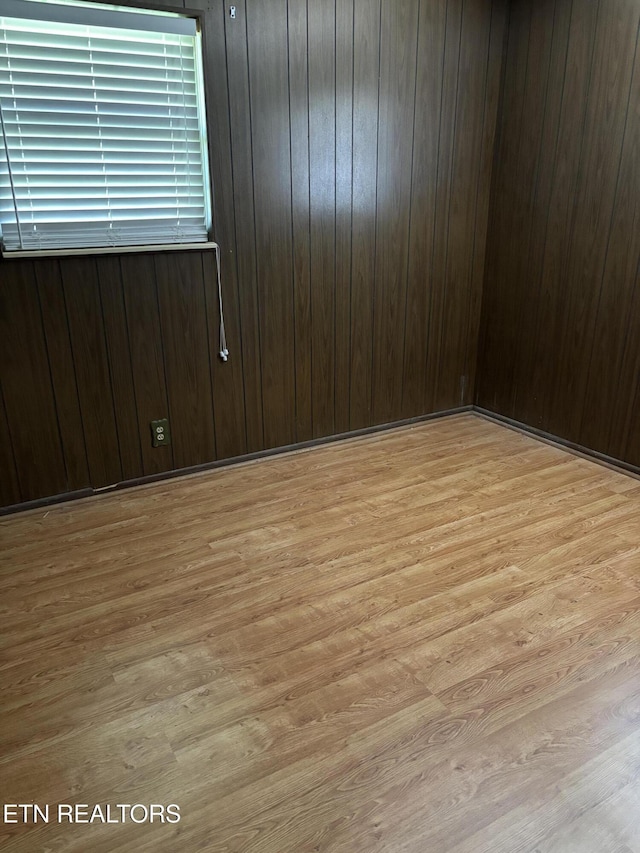 spare room with wooden walls and light wood-type flooring