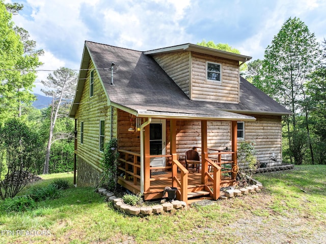 back of house featuring a lawn, a deck, a shingled roof, and faux log siding