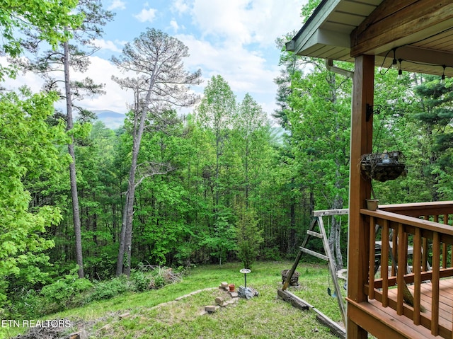 view of yard featuring a wooden deck and a forest view