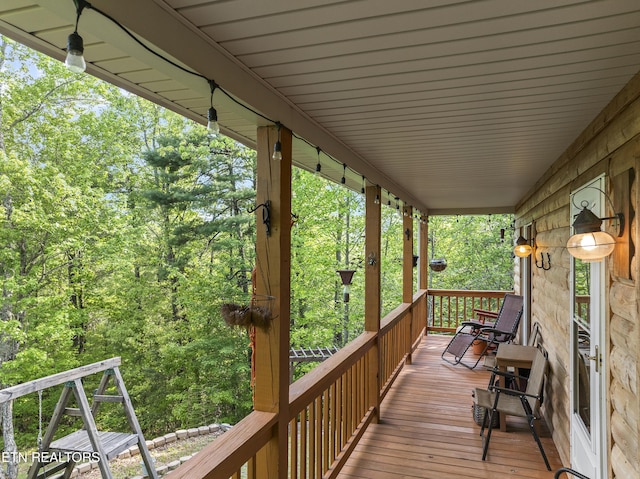 deck with a porch and a view of trees