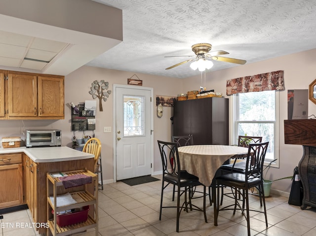 dining room featuring a toaster, baseboards, light tile patterned floors, and a ceiling fan