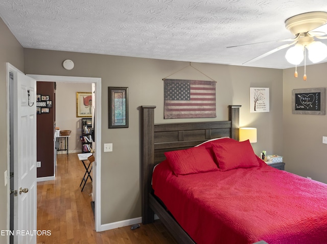 bedroom featuring baseboards, a ceiling fan, a textured ceiling, and wood finished floors
