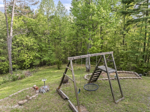 view of jungle gym with a yard and a wooded view