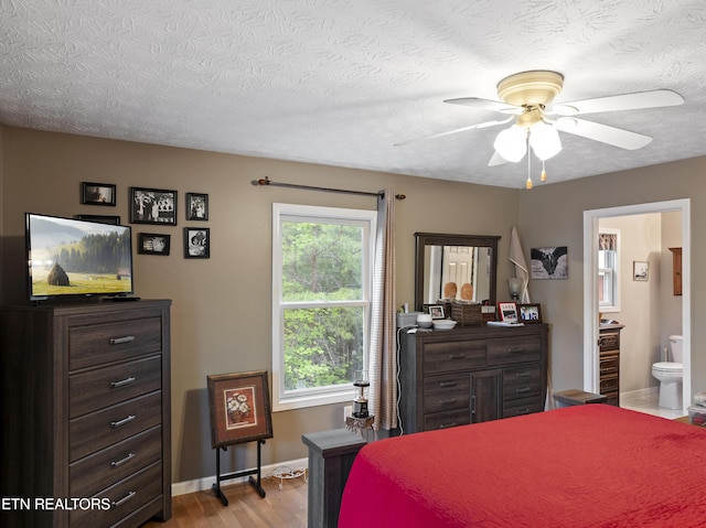 bedroom featuring a ceiling fan, a textured ceiling, baseboards, connected bathroom, and light wood-style flooring