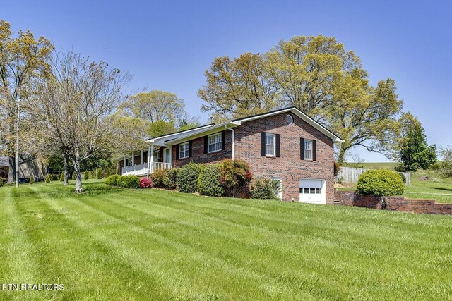 view of front of home with an attached garage, brick siding, and a front lawn